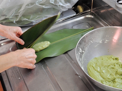 巻く|キレイに洗って乾かしておいたサンニンの葉に、適当な大きさに生地を整えて包んでいきます。 <br />（サンニンの葉は、あらかじめ少し蒸しておくと包みやすくなります。さらに葉の裏側に包むことで食べるときに餅が剥がれやすくなります。）<br />最後に蒸したときに餅がはみ出さないようにヒモでしっかり結びます。